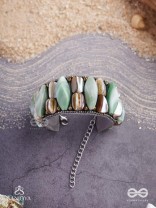 Shuktimālā- Shell band-Expandable bracelet crafted from shell beads, combining turquoise and beige-brown tones with a brassy finish.