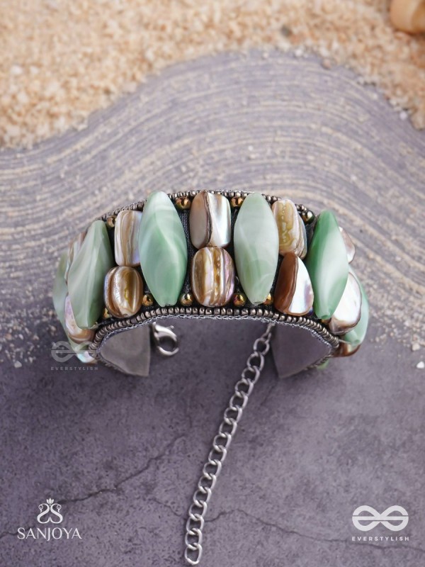 Shuktimālā- Shell band-Expandable bracelet crafted from shell beads, combining turquoise and beige-brown tones with a brassy finish.