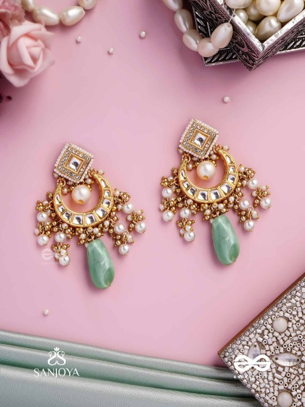 PURNIMA PHOOL – FULL MOON FLOWER AN EXQUISITE KUNDAN EARRING FEATURING GOLDEN DESIGNS, PEARL CLUSTERS, AND A GREEN GEMSTONE DROP, SYMBOLIZING ELEGANCE