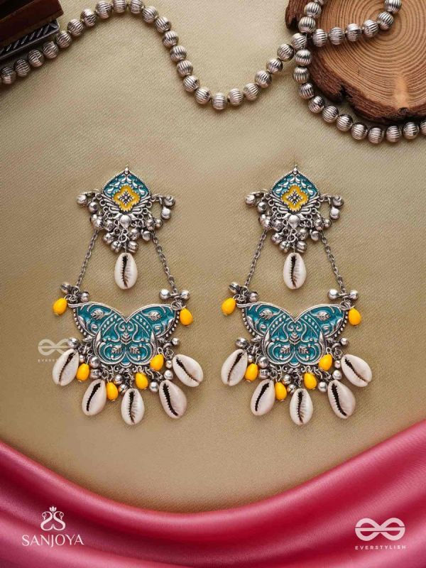 SHANKHA PUSHPA- CONCH BLOSSOM-OXIDIZED EARRINGS WITH PASTEL-HUED METALWORK, EMBELLISHED WITH DELICATE COWRIE SHELLS, YELLOW BEADS AND GHUNGROO
