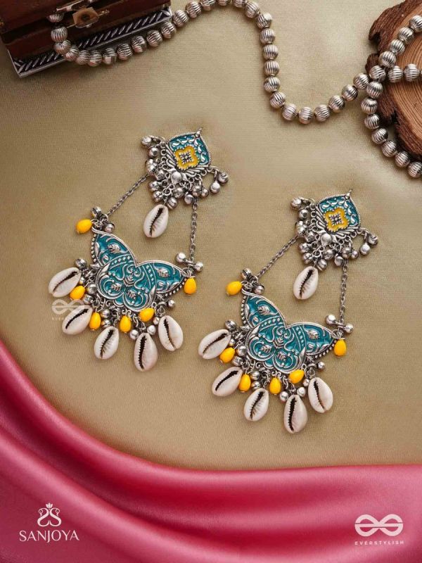 SHANKHA PUSHPA- CONCH BLOSSOM-OXIDIZED EARRINGS WITH PASTEL-HUED METALWORK, EMBELLISHED WITH DELICATE COWRIE SHELLS, YELLOW BEADS AND GHUNGROO
